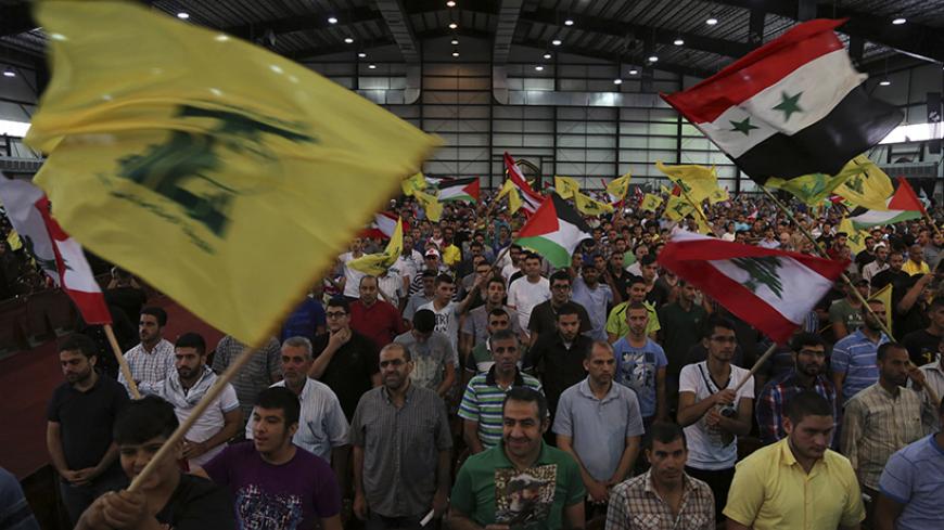 Hezbollah supporters wave Lebanese, Syrian, Palestinian and Hezbollah flags as they listen to their leader Sayyed Hassan Nasrallah addressing his supporters during a rally to mark "Quds (Jerusalem) Day" in Beirut's southern suburbs July 25, 2014. REUTERS/Sharif Karim (LEBANON - Tags: POLITICS CIVIL UNREST RELIGION) - RTR4056R