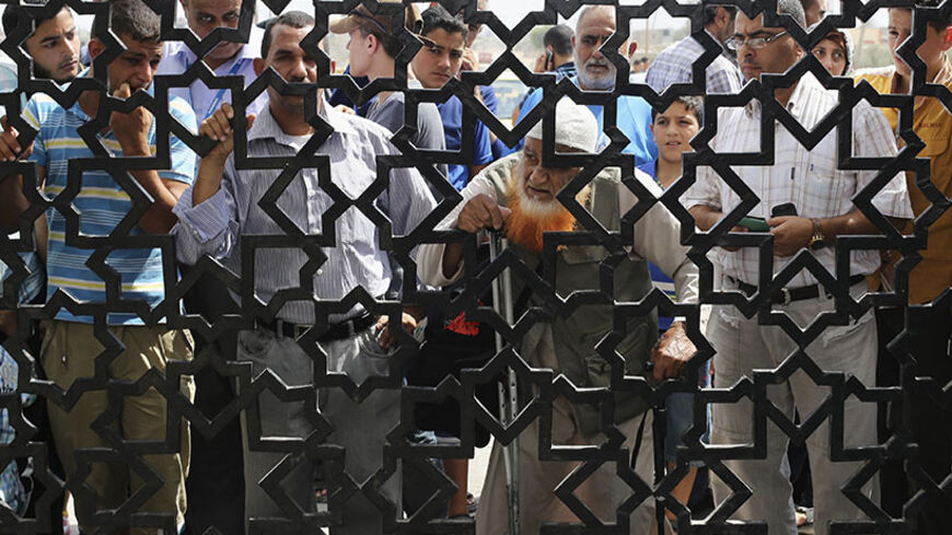 People, hoping to cross into Egypt, stand behind a gate as they wait at the Rafah crossing between Egypt and the southern Gaza Strip August 5, 2014. Israel pulled its ground forces out of the Gaza Strip on Tuesday and began a 72-hour truce with Hamas mediated by Egypt as a first step towards negotiations on a more enduring end to the month-old war. Gaza officials say the war has killed 1,834 Palestinians, most of them civilians. Israel says 64 of its soldiers and three civilians have been killed since figh
