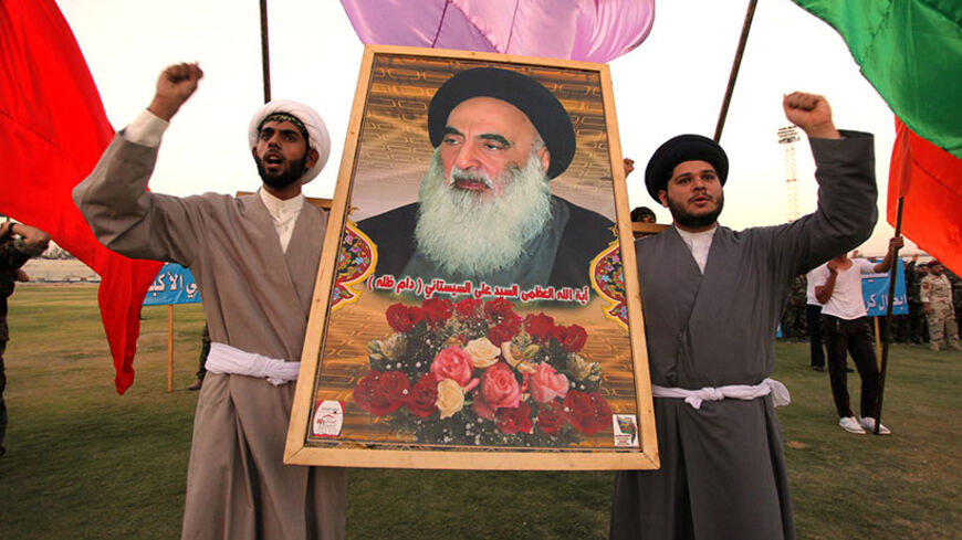 Shi'ite volunteers, who have joined the Iraqi army to fight against militants of the Islamic State, formerly known as the Islamic State in Iraq and the Levant (ISIL), carry a picture of Grand Ayatollah Ali Sistani during a graduation ceremony after completing their field training in Najaf, August 16, 2014. School is out, but northern Baghdad's classrooms are packed - not with students, but with people who have travelled further than most to escape the Sunni militant onslaught splitting Iraq. REUTERS/Alaa Al