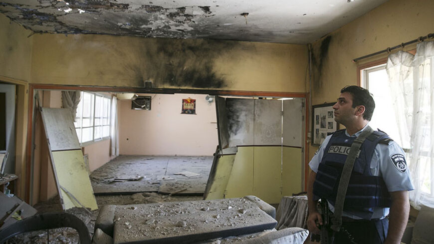 An Israeli policeman surveys a building damaged from a Palestinian mortar salvo in a community outside the central Gaza Strip August 21, 2014. Israel killed three senior Hamas commanders in an air strike on the Gaza Strip on Thursday, the clearest signal yet that Israel is intent on eliminating the group's military leadership after a failed attempt on the life of its top commander this week. After six weeks of conflict in which more than 2,000 Palestinians have been killed, most of them civilians, Israeli a