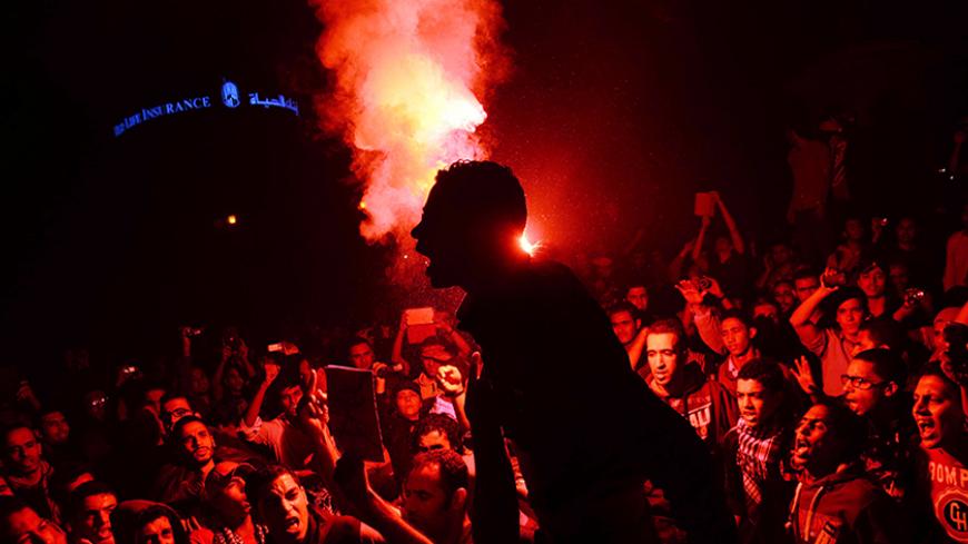 Egyptian protesters use flare lights at Talaat Harb Square in downtown Cairo on November 26, 2013 during a clash with police after the security forces dispersed protesters from a demonstration organized by human rights group "No Military Trials for Civilians" in the first unauthorised protest staged in the capital since the adoption of a law that regulates demonstrations. Egypt's interim president Adly Mansour passed a law that allows security forces to gradually step up force while dispersing protestors. A