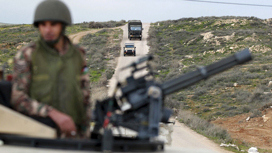 A Jordanian soldier stands guard in his tank as Jordanian army vehicles carrying Syrian refugees drive towards it at the Jordan-Syrian border near Mafraq February 18, 2013. According to the Jordanian Armed Forces sources, around 89,000 Syrian refugees fleeing from the violence in their country have crossed the Jordanian border since the beginning of 2013. REUTERS/Muhammad Hamed (JORDAN - Tags: POLITICS MILITARY) - RTR3DYZ6