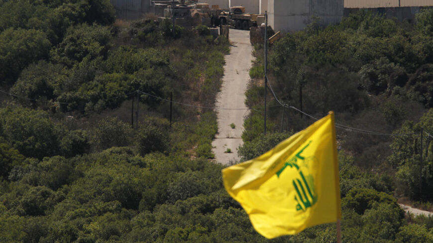 Israeli soldiers and trucks are seen from the southern Lebanese village Marwaheen, as a Hezbollah flag flutters during a protest in solidarity with Palestinian people in Gaza near the Lebanese-Israeli border July 25, 2014. The protest was organised by Hezbollah with the participation of Shi'ite and Sunni Muslim Sheikhs, against Israel's military action in Gaza and marking the annual al-Quds Day. REUTERS/Ali Hashisho   (LEBANON - Tags: POLITICS CIVIL UNREST RELIGION MILITARY) - RTR403PX