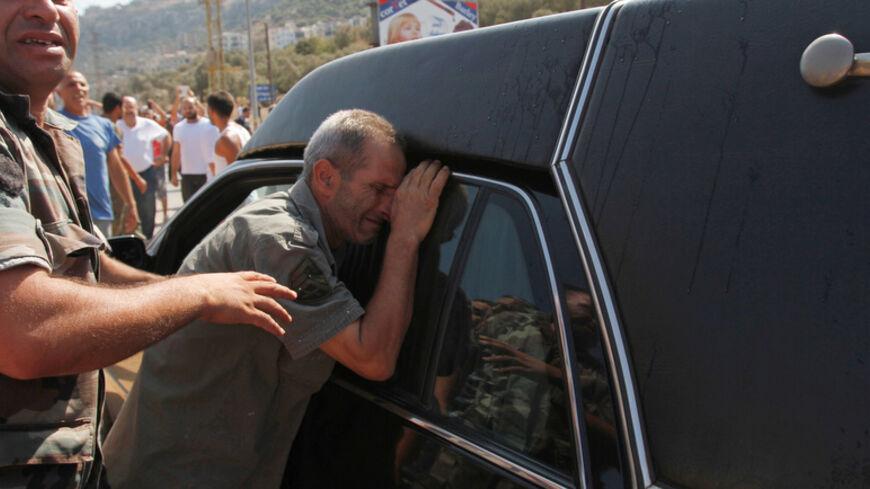 A father of a Lebanese soldier captured by hardline Syrian Islamists, reacts next to a hearse carrying the coffin of another soldier Ali al-Sayyed, who was beheaded by Islamic State militants in Arsal, during his funeral in Qalamoun, in Akkar September 3, 2014. Islamic State militants beheaded al-Sayyed, one of 19 Lebanese soldiers captured by hardline Syrian Islamists when they seized the Lebanese border town for a few days last month, a video posted on social media showed on Saturday. REUTERS/Omar Ibrah