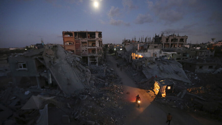 Palestinian pedestrians and a motorcyclist commute along a road between ruins of houses, which witnesses said were damaged or destroyed during the Israeli offensive, in Beit Hanoun town in the northern Gaza Strip September 7, 2014. An open-ended ceasefire between Israel and Hamas-led Gaza militants, mediated by Egypt, took effect on August 26 after a seven-week conflict. It called for an indefinite halt to hostilities, the immediate opening of Gaza's blockaded crossings with Israel and Egypt, and a widening