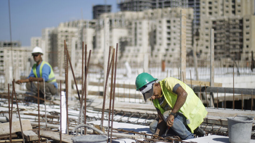 Palestinian labourers work at a construction site in the new Palestinian town dubbed Rawabi or "The Hills", near the West Bank city of Ramallah October 27, 2013. The crackdown on the Gaza Strip as Egypt demolishes the smuggling tunnels along its sandy border, and stagnation in the West Bank mean the Palestinian economy might shrink this year after average annual growth of about nine percent in 2008-2011. To match Analysis PALESTINIANS-ECONOMY/ REUTERS/Mohamad Torokman (WEST BANK - Tags: POLITICS BUSINESS