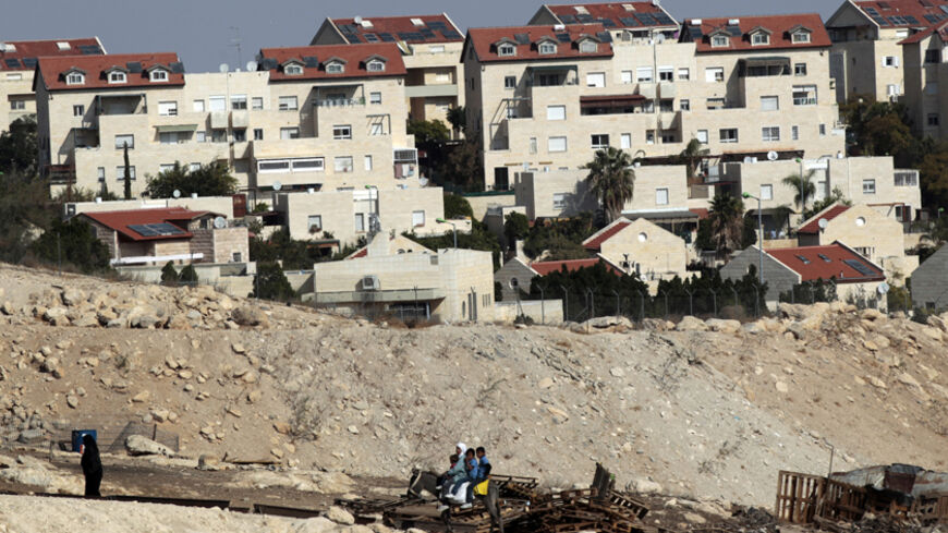 Palestinians ride on a donkey near homes in the West Bank Jewish settlement of Maale Adumim, near Jerusalem November 13, 2013. Palestinian President Mahmoud Abbas said on Wednesday his peace negotiators had resigned over the lack of progress in U.S.-brokered statehood talks clouded by Israeli settlement building. REUTERS/Ammar Awad (WEST BANK - Tags: POLITICS SOCIETY ANIMALS) - RTX15BNX