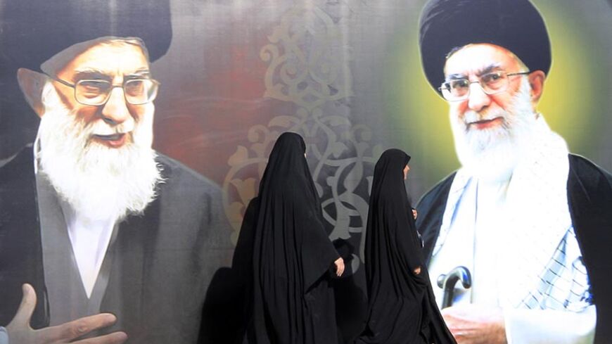 Iraqi women walk past a poster depicting images of Shi'ite Iran's Supreme Leader Ayatollah Ali Khamenei at al-Firdous Square in Baghdad February 12, 2014. An Iraqi daily newspaper stopped publishing after two bombs were planted in the entrance to its headquarters in Baghdad on Monday and after threats from an Iranian-backed Shi'ite militia. Editors and reporters at Assabah AlJadeed said they had received death threats from the influential Asaib al-Haq militia in response to what it had described as an "insu