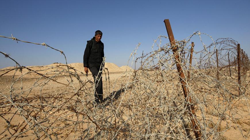 An Egyptian soldier stands behind a barbed wire fence on the border between Israel and Egypt some 50 km (30 miles) north of Eilat in this November 28, 2010 file photo, after work begun to construct a barrier to seal off part of the border with Egypt's Sinai desert. Arms smuggling by Bedouin tribal networks, mainly by land along Egypt's southern border with Sudan, across the Sinai peninsula and into the Hamas-run Gaza Strip is on the uptick, according to an Egyptian official, who asked not to be named. Sudan