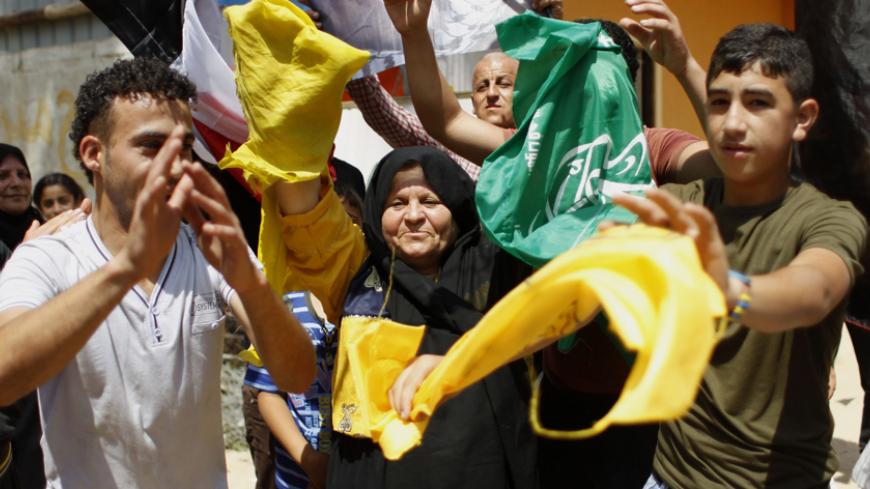 Palestinian protesters wave the flags of Palestinian political movements, Fatah (yellow) and Hamas (green) as they chant slogans in support of the national reconciliation and the announcement of the formation of a national unity government between the two factions, during a rally it Khan Yunis, in the southern Gaza Strip, on May 29, 2014. Palestinian premier Rami Hamdallah is to head the consensus government to be formed under a deal with Hamas to end seven years of rival administrations in the West Bank an