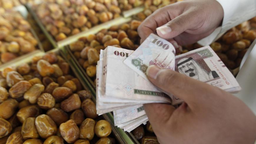 A man counts Saudi riyal during the Festival of Dates in Buraidah, north of Riyadh September 1, 2012. REUTERS/Fahad Shadeed (SAUDI ARABIA - Tags: FOOD SOCIETY) - RTR37D1Q