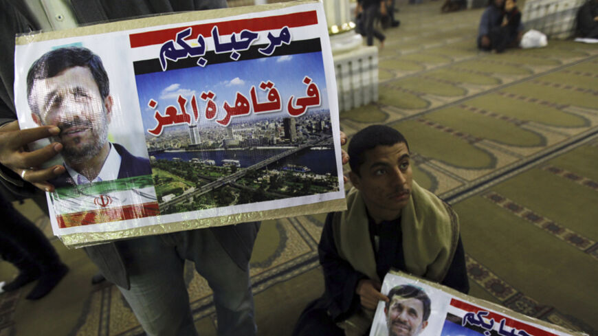 People hold posters with an image of Iran's President Mahmoud Ahmadinejad at the Al-Hussein mosque, named after Prophet Mohammed's grandson Hussein ibn Ali, before Ahmadinejad's visit to the mosque in old Cairo February 5, 2013. Ahmadinejad was both kissed and scolded on Tuesday when he began the first visit to Egypt by an Iranian president since Tehran's 1979 Islamic revolution. The trip was meant to underline a thaw in relations since Egyptians elected an Islamist head of state, President Mohamed Mursi, l
