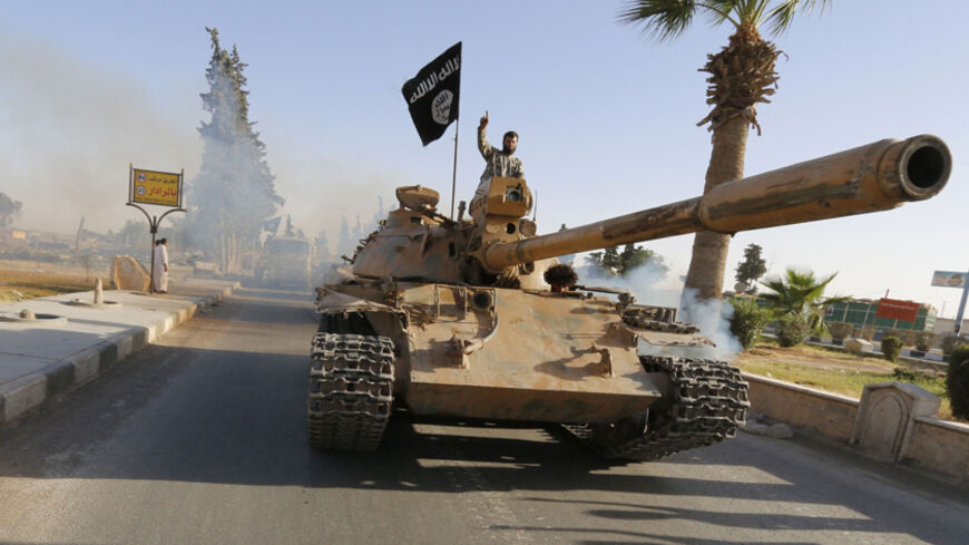 Militant Islamist fighters on a tank take part in a military parade along the streets of northern Raqqa province June 30, 2014. Militant Islamist fighters held a parade in Syria's northern Raqqa province to celebrate their declaration of an Islamic "caliphate" after the group captured territory in neighbouring Iraq, a monitoring service said. The Islamic State, an al Qaeda offshoot previously known as Islamic State in Iraq and the Levant (ISIL), posted pictures online on Sunday of people waving black flags