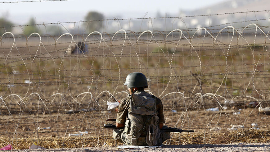 A Turkish soldier sits on the Turkish-Syrian border near the southeastern town of Suruc in Sanliurfa province September 22, 2014. More than 130,000 Syrian Kurds fleeing an advance by Islamic State militants have crossed into Turkey in the past three days and the authorities are preparing for more, Turkish Deputy Prime Minister Numan Kurtulmus said on Monday.  REUTERS/Murad Sezer (TURKEY - Tags: POLITICS MILITARY CIVIL UNREST CONFLICT) - RTR476RO
