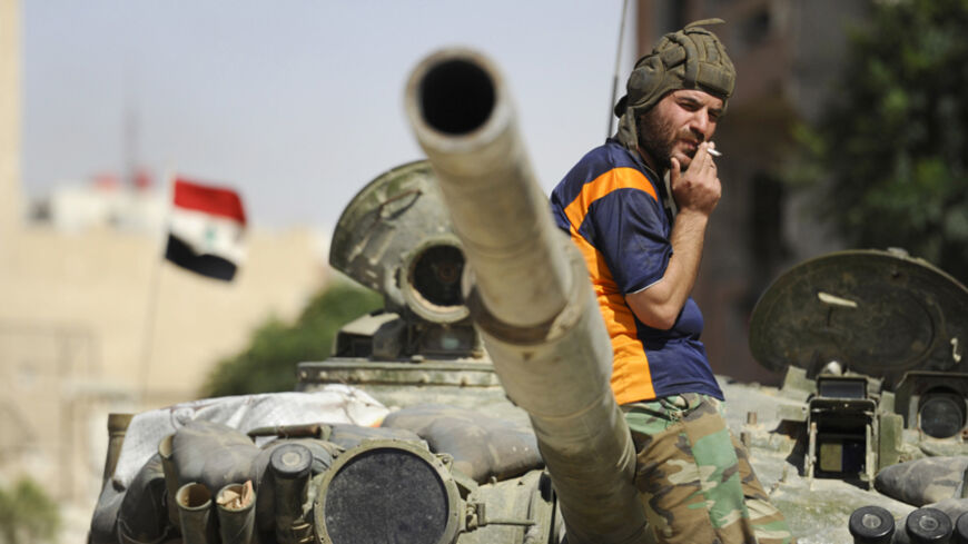A soldier loyal to Syria's President Bashar Al-Assad smokes while resting on a tank in Adra al-Omalia, after taking control of the area from rebel fighters September 25, 2014. Syrian government forces overran rebels in the town northeast of Damascus on Thursday, strengthening al-Assad's grip on territory around the capital. The town - Adra al-Omalia - is about 30 km (19 miles) from central Damascus but far from parts of Syria where the United States has launched air strikes against Islamic State militants. 