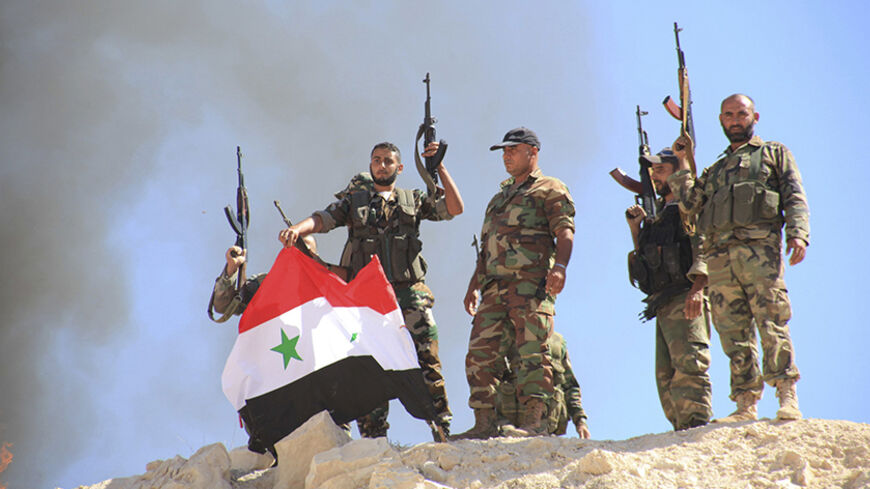 Forces of Syria's President Bashar al-Assad erect the Syrian national flag after burning a flag of al Qaeda-linked Nusra Front, which they said was left behind by rebel fighters in Zor al-Mahruqa village, after the forces said they had regained control of the area and its surrounding hills in the Hama countryside October 6, 2014. REUTERS/George Ourfalian (SYRIA - Tags: POLITICS CIVIL UNREST CONFLICT) - RTR4942P