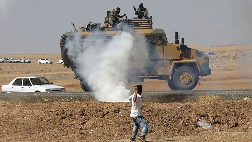 A protester throws stones at an armoured army vehicle during a pro-Kurdish demonstration in solidarity with people of Kobani, near the Mursitpinar border crossing on the Turkish-Syrian border, in the Turkish town of Suruc in southeastern Sanliurfa province October 7, 2014. Islamic State fighters advanced into the south west of the Syrian Kurdish town of Kobani overnight, a monitoring group said on Tuesday, taking several buildings to gain attacking positions from two sides of the city. REUTERS/Umit Bektas