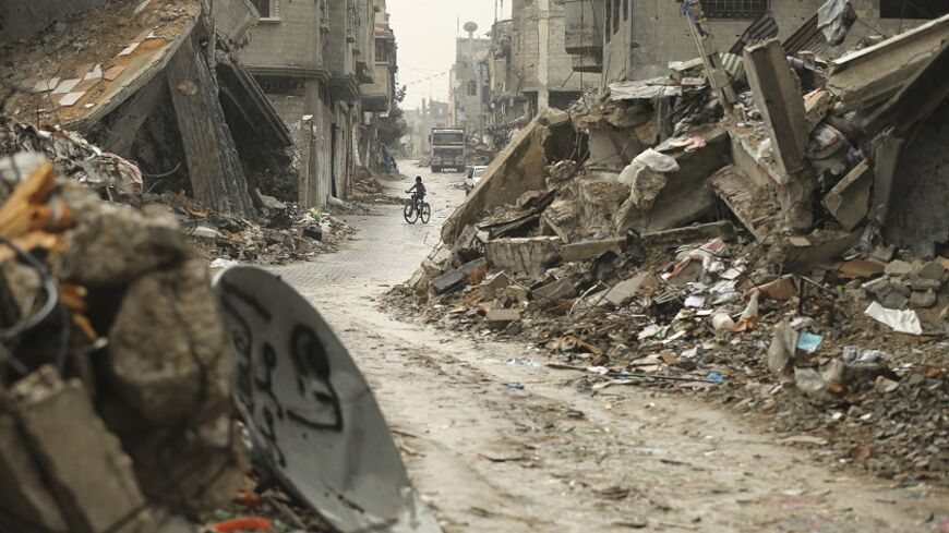 A Palestinian boy rides a bicycle past the ruins of houses that witnesses said were destroyed during a seven-week Israeli offensive, on a rainy day in the east of Gaza City October 19, 2014. An open-ended ceasefire between Israel and Hamas-led Gaza militants, mediated by Egypt, took effect on August 26 after a seven-week conflict. It called for an indefinite halt to hostilities, the immediate opening of Gaza's blockaded crossings with Israel and Egypt, and a widening of the territory's fishing zone in the M