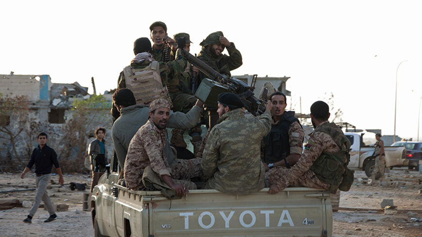 Members of forces loyal to former general Khalifa Haftar ride in a truck in the Benina area, east of Benghazi October 24, 2014. Violent clashes have taken place over the past few weeks between these forces loyal to Haftar and both the Islamist group, the Shura Council of Libyan Revolutionaries, and an alliance of former anti-Gaddafi rebels Ansar al-Sharia, for control of the airport nearby. The two latter groups have now withdrawn and the area is being controlled by these forces loyal to Haftar. Libya's ar