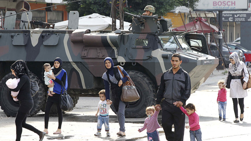 Civilians walk past a Lebanese army soldier patrolling on an armoured vehicles after being deployed to tighten security following clashes between Lebanese soldiers and Islamist gunmen in Tripoli, northern Lebanon, October 27, 2014. Guns fell silent in the northern Lebanese city of Tripoli on Monday after two days of deadly battles between the army and Islamist gunmen, some of the worst fighting to spill over into Lebanon from Syria's civil war next door. REUTERS/Mohamed Azakir (LEBANON - Tags: POLITICS CIVI