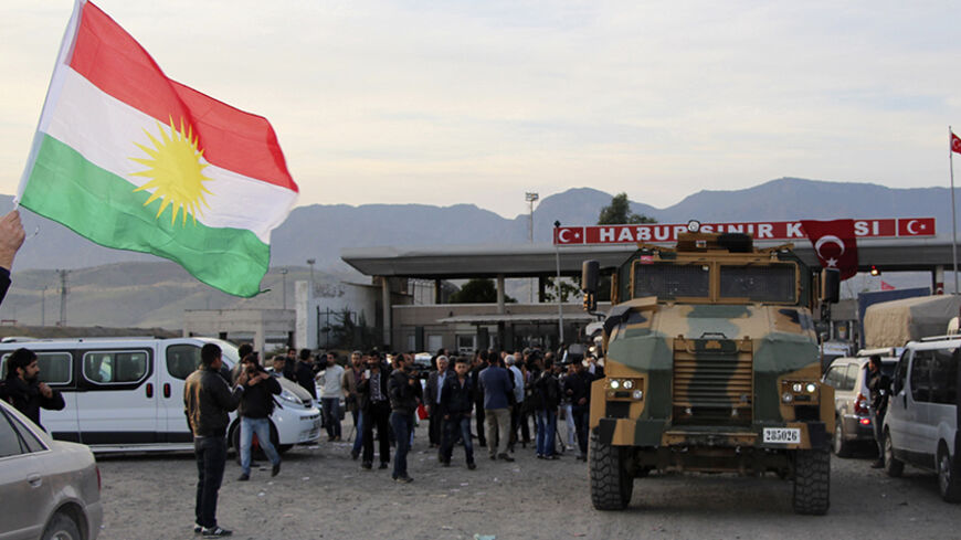 A man waves a Kurdistan flag as a Turkish military truck escorts a convoy of peshmerga vehicles at Habur border gate, which separates Turkey from Iraq, near the town of Silopi in southeastern Turkey, October 29, 2014. Iraqi peshmerga fighters arrived in southeastern Turkey early on Wednesday ahead of their planned deployment to the Syrian town of Kobani to help fellow Kurds repel an Islamic State advance, a Reuters witness said. REUTERS/Kadir Baris (TURKEY - Tags: POLITICS MILITARY CONFLICT TPX IMAGES OF TH