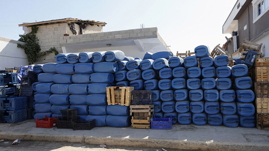 Blue jerry cans usually used by smugglers ferrying fuel smuggled into Turkey from over the border in Syria are stacked in front of a shop for sale in Turkish border town of Hacipasa, Hatay province, September 8, 2013. Each night, a stream of beaten-up cars and trucks weighed down with blue jerry cans rumbles along the muddy lane, ferrying fuel smuggled into Turkey from over the border in Syria. The thousands of liters of diesel that make their way by cover of darkness to Turkey's southern Hatay province are