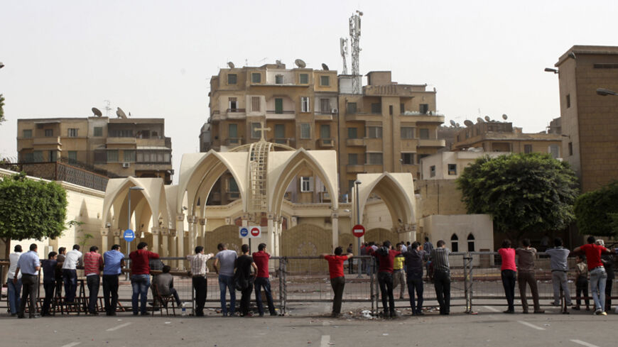 Coptic Christians stand near a make shift fence in Cairo's main Coptic cathedral after Sunday's clashes with Muslims in Cairo, April 8, 2013. After days of fighting at the cathedral and a town outside Cairo killing eight - the worst sectarian strife since Islamist President Mohamed Mursi was elected in June - many Copts now question whether they have a future in Egypt.  Picture taken April 8, 2013. REUTERS/Asmaa Waguih (EGYPT  - Tags: RELIGION POLITICS CIVIL UNREST) - RTXYHPU
