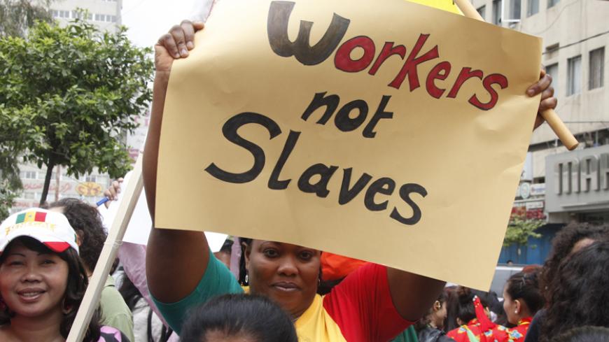 A migrant domestic worker holds up a placard during a parade in Beirut, to support the rights of migrant domestic workers in Lebanon, ahead of May Day, April 29, 2012. The domestic worker industry in Lebanon is vast - foreign maids account for more than five percent of the population - and the sector is plagued by archaic labour laws, inhumane practices and dire wages. REUTERS/ Mohamed Azakir (LEBANON - Tags: CIVIL UNREST BUSINESS EMPLOYMENT POLITICS) - RTR31DDR