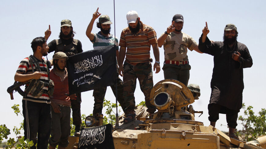 Islamist Syrian rebel group Jabhat al-Nusra members gesture while posing on a tank on Al-Khazan frontline of Khan Sheikhoun, northern Idlib province May 17, 2014. REUTERS/Hamid Khatib (SYRIA - Tags: CIVIL UNREST MILITARY POLITICS CONFLICT) - RTR3PM9N