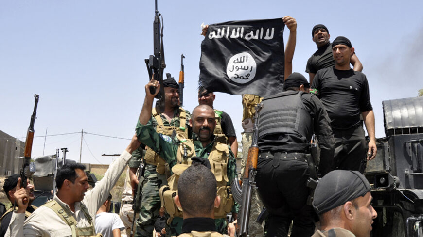 Iraqi security forces pull down a flag belonging to Sunni militant group Islamic State of Iraq and the Levant (ISIL) during a patrol in the town of Dalli Abbas in Diyala province, June 30, 2014. The leader of the al Qaeda offshoot now calling itself the Islamic State has called on Muslims worldwide to take up arms and flock to the "caliphate" it has declared on captured Syrian and Iraqi soil. Picture taken June 30, 2014. REUTERS/Stringer (IRAQ - Tags: CIVIL UNREST POLITICS MILITARY TPX IMAGES OF THE DAY) - 