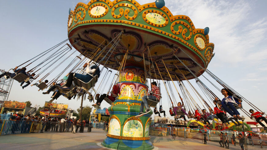 Residents take a ride at an amusement park as they celebrate the Muslim festival of Eid-al-Adha in Baghdad October 5, 2014. Muslims around the world celebrate Eid al-Adha to mark the end of the haj pilgrimage by slaughtering sheep, goats, camels and cows to commemorate Prophet Abraham's willingness to sacrifice his son, Ismail, on God's command. REUTERS/Ahmed Saad (IRAQ - Tags: RELIGION) - RTR490NA