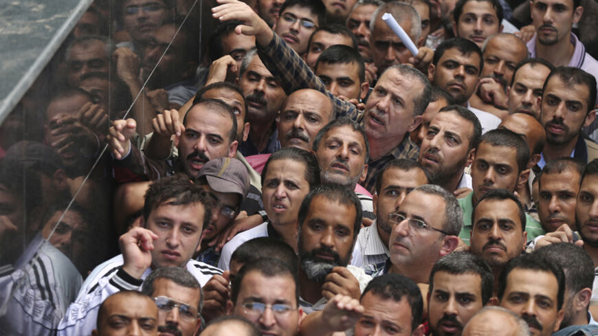 Palestinian Hamas-hired civil servants wait to receive payment outside a post office in Gaza City October 29, 2014. Some 24,000 civil servants hired by the Islamist group Hamas, many of whom have not received a full salary in almost a year, finally got some pay on Wednesday from the new Palestinian unity government based in the West Bank. The funds were supplied by the gas-rich kingdom of Qatar, which is an ally of Hamas. But the fact the cash was delivered by the West Bank administration gave a boost to ho