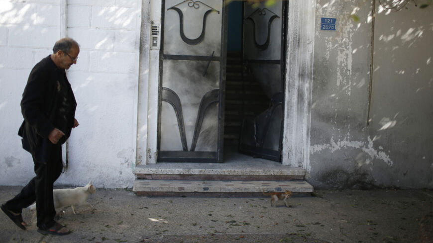 A man walks past a damaged door of a Fatah official's home after an explosion in Gaza City November 7, 2014. A series of small explosions targeted the homes and vehicles of officials from President Mahmoud Abbas's Fatah movement in the Gaza Strip on Friday, members of the party and witnesses said, causing minor damage but no injuries. REUTERS/Mohammed Salem (GAZA - Tags: POLITICS CIVIL UNREST) - RTR4D84E
