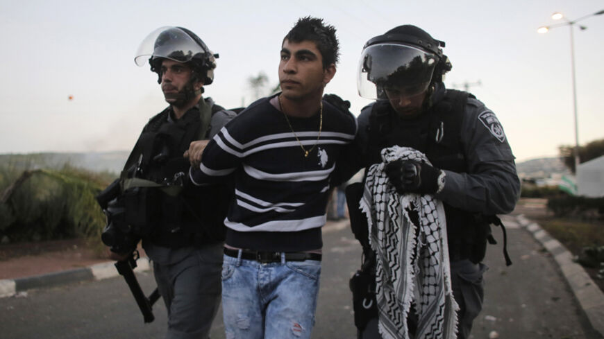 Israeli policemen detain an Arab youth during clashes at the entrance to the town of Kfar Kanna, north of Israel, November 8, 2014. Thousands took to the streets on Saturday hours after Khayr al-Din al-Hamdan was shot by police, after he attacked them as they came to arrest a relative. REUTERS/Ammar Awad (ISRAEL - Tags: POLITICS CIVIL UNREST RELIGION) - RTR4DDLH