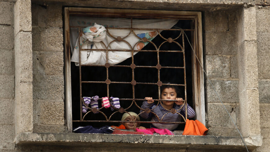 Children look out of their house window as they watch the funeral of 32-year-old Palestinian man Fadel Halawa, whom medics said was shot dead by Israeli forces, in Gaza City November 23, 2014.  The Palestinian Health Ministry said Israeli forces shot dead Halawa in the northern Gaza Strip on Sunday, the first such fatality since a 50-day Gaza war ended in August. The Israeli military had no immediate comment. One of Halawa's relatives said he had been searching for song birds, which nest in trees near the I