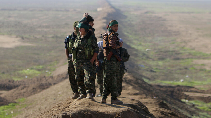 Female fighters of the Kurdish People's Protection Units (YPG) stand near the border between Syria and Iraq, close to the Iraqi town of Snoun December 22, 2014. On Sunday, Kurdish and Yazidi fighters battled to take the Sinjar back from Islamic State after breaking a months-long siege of the mountain above it. Seizing the town would restore the majority of territory Iraq's Kurds lost in Islamic State's surprise offensive in August Picture taken December 22, 2014. REUTERS/Stringer (IRAQ - Tags: POLITICS CIVI