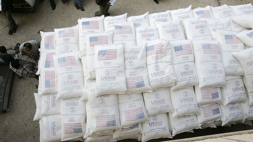 Palestinians stand beside a truck loaded with sacks of flour received from The United States Agency for International Development (USAID) in the village of Anin near the West Bank city of Jenin June 4, 2008. REUTERS/Mohamad Torokman (WEST BANK) - RTX6I8P
