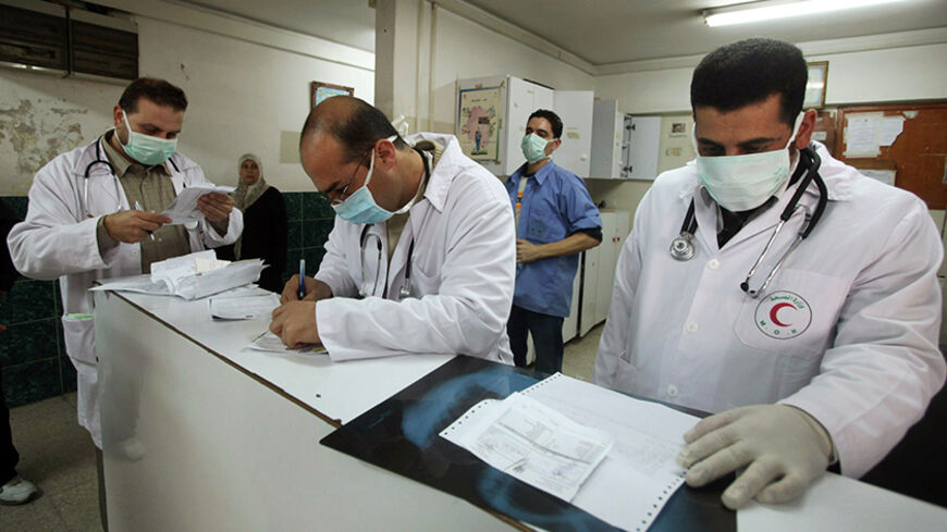 Palestinian doctors wear face masks at the reception of al-Shifa hospital in Gaza City December 6, 2009. H1N1 swine flu has finally reached the Gaza Strip, the health ministry said on Sunday, worrying Palestinians who had credited Israel's blockade of the territory with keeping the virus at bay. REUTERS/Mohammed Salem (GAZA POLITICS HEALTH) - RTXRJIC