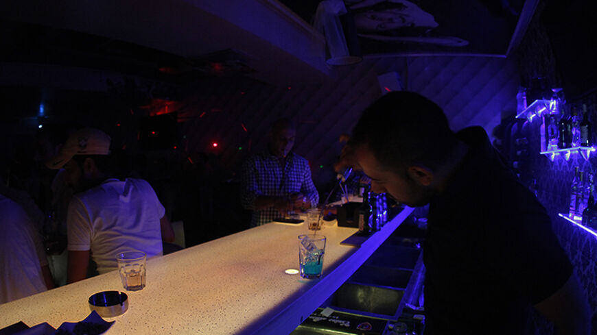 TO GO WITH AFP STORY BY SAMMY KETZ 
A bar man serves drinks at a nightclub in downtown Damascus on September 12, 2013. When night falls in Damascus, gaggles of determined revellers still head out on the town seeking to drown out the thunder of outgoing artillery fire with the boom of music. AFP PHOTO / ANWAR AMRO        (Photo credit should read ANWAR AMRO/AFP/Getty Images)