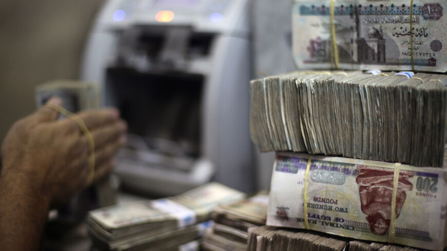 An employee counts money at an exchange office in downtown Cairo June 5, 2014. Egypt's currency black market is under threat from two directions, as aid from wealthy Gulf states promises to ease a dollar shortage and an increasingly confident central bank engineers a gradual depreciation of the Egyptian pound. REUTERS/Amr Abdallah Dalsh  (EGYPT - Tags: POLITICS BUSINESS) - RTR3SDW1