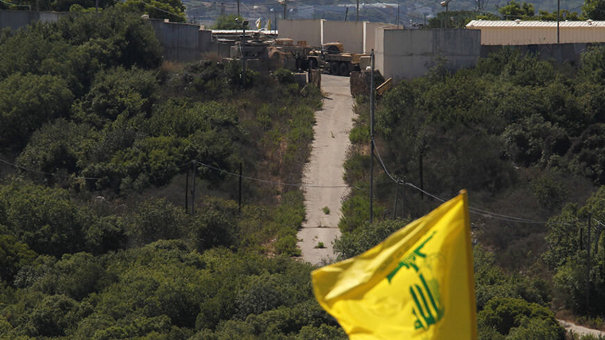 Israeli soldiers and trucks are seen from the southern Lebanese village Marwaheen, as a Hezbollah flag flutters during a protest in solidarity with Palestinian people in Gaza near the Lebanese-Israeli border July 25, 2014. The protest was organised by Hezbollah with the participation of Shi'ite and Sunni Muslim Sheikhs, against Israel's military action in Gaza and marking the annual al-Quds Day. REUTERS/Ali Hashisho   (LEBANON - Tags: POLITICS CIVIL UNREST RELIGION MILITARY) - RTR403PX