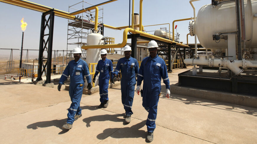 Iraqi workers walk through the Taq Taq oil field in Arbil, in Iraq's Kurdistan region, August 16, 2014. Picture taken August 16, 2014. REUTERS/Azad Lashkari (IRAQ - Tags: ENERGY BUSINESS COMMODITIES) - RTR43SUK