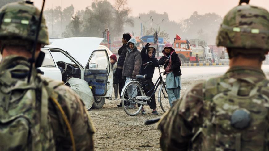 Afghan children gesture at U.S. soldiers from Grim Company of the 3rd Cavalry Regiment as they stand guard near an Afghan police checkpoint during a mission near Forward Operating Base Fenty in the Nangarhar province of Afghanistan December 19, 2014. REUTERS/Lucas Jackson (AFGHANISTAN - Tags: CIVIL UNREST POLITICS MILITARY CONFLICT) - RTR4INDK