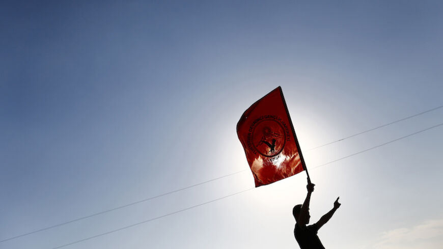 A boy holds the Kurdish PKK youth organization flag during the funeral of three Kurdish fighters killed during clashes against Islamic State in Syrian town of Kobani, at a cemetery in the southeastern town of Suruc, Sanliurfa province October 24, 2014. REUTERS/Kai Pfaffenbach (TURKEY - Tags: MILITARY CONFLICT POLITICS CIVIL UNREST TPX IMAGES OF THE DAY) - RTR4BHCQ