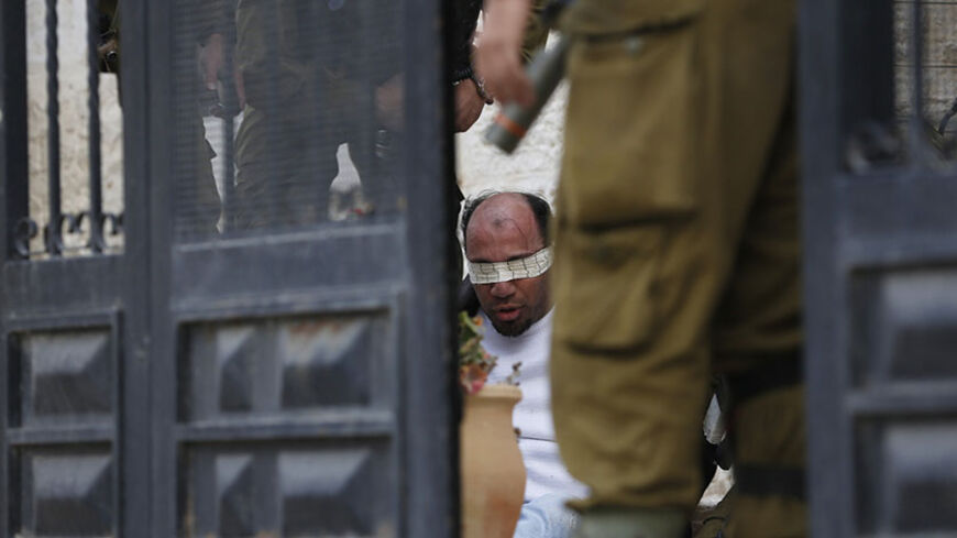 Israeli soldiers stand next to a Palestinian man they detained during clashes with stone-throwing protesters at a weekly demonstration against the West Bank Jewish settlement of Beit El, in Jalazoun refugee camp, near Ramallah February 14, 2014. REUTERS/Mohamad Torokman (WEST BANK - Tags: POLITICS CIVIL UNREST) - RTX18TLF