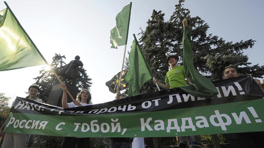 People take part in a rally to support Libya's leader Muammar Gaddafi and protest against the NATO military operation in Libya in the Russian city of Rostov-on-Don July 7, 2011. The banner reads "NATO: Hands off Libya! Russia is with you, Gaddafi".  REUTERS/Sergei Karpov  (RUSSIA - Tags: POLITICS CONFLICT CIVIL UNREST) - RTR2OKXP