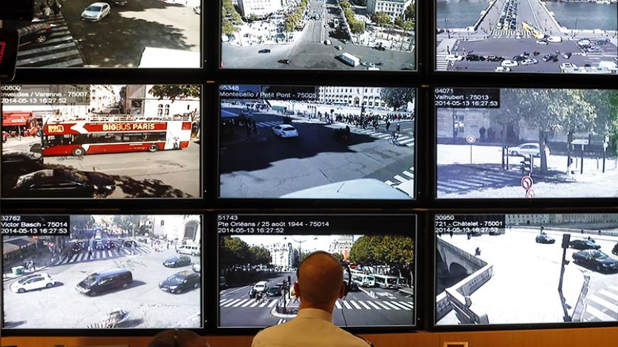 A policeman look at screens at the Paris Prefecture control room May 13, 2014, which display images from more than 1000 cameras which are used to monitor traffic circulation, principle monuments and public areas in the French capital.  Picture taken May 13, 2014. REUTERS/Charles Platiau (FRANCE - Tags: SCIENCE TECHNOLOGY CRIME LAW) - RTR3P5DI