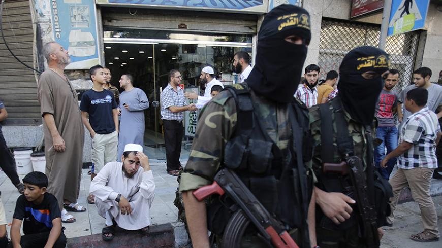 A Palestinian man watches as Islamic Jihad militants take part in a rally celebrating what they say was a victory over Israel following a ceasefire in Gaza City August 29, 2014. An open-ended ceasefire, mediated by Egypt, took effect on Tuesday evening. It called for an indefinite halt to hostilities, the immediate opening of Gaza's blockaded crossings with Israel and Egypt, and a widening of the territory's fishing zone in the Mediterranean. Israel launched an offensive on July 8, with the declared aim of 