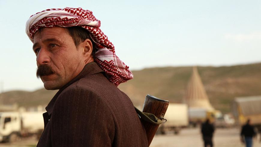 A man from the minority Yazidi sect stands guard at Mount Sinjar, in the town of Sinjar, December 20, 2014. Iraqi Kurdish fighters flashed victory signs as they swept across the northern side of Sinjar mountain on Saturday, two days after breaking through to free hundreds of Yazidis trapped there for months by Islamic State fighters. REUTERS/Ari Jalal (IRAQ - Tags: POLITICS CIVIL UNREST MILITARY) - RTR4IV2I