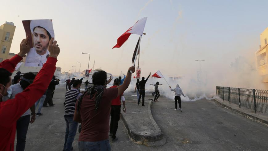 Protesters holding a Bahraini flags and a photo of the leader of Bahrain's main opposition party Al Wefaq, Ali Salman, shout anti-government slogans during clashes in the village of Bilad Al Qadeem south of Manama, January 6, 2015.
Bahraini police fired rubber bullets and tear gas to scatter protesters who gathered outside the home of Sheikh Ali Salman, a Shi'ite Muslim opposition leader on Monday, witnesses said, after he was remanded in custody for a further 15 days. Around 100 protesters angry at the d